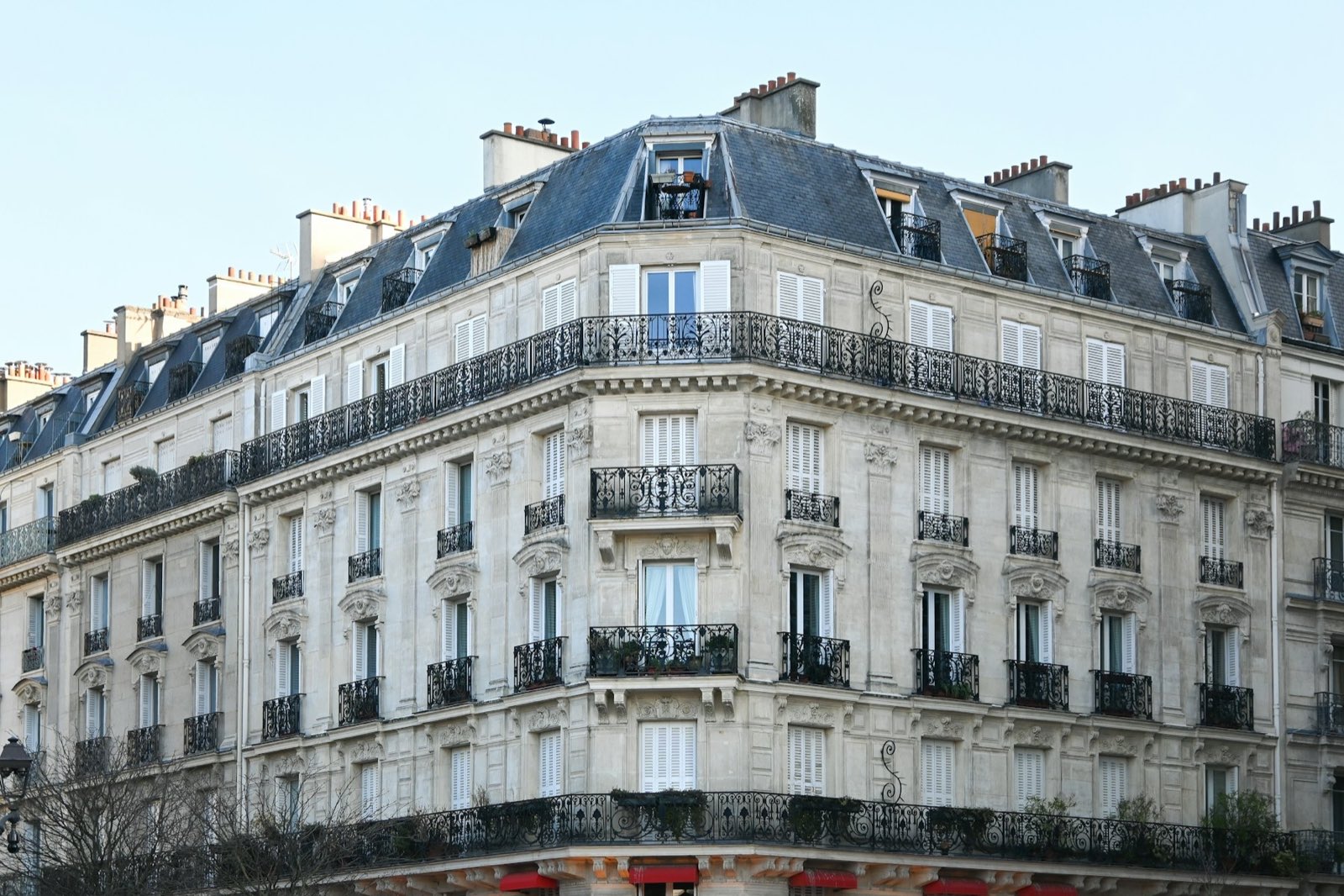 Immeuble haussmannien d'angle en pierre de taille avec balcons en fer forgé.