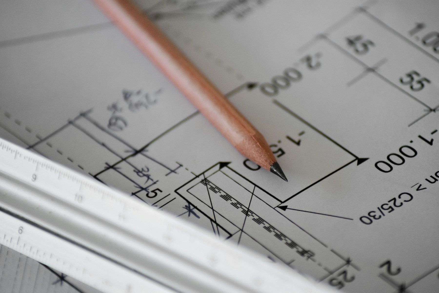 Crayon et règle posés sur un plan d'architecte coté.